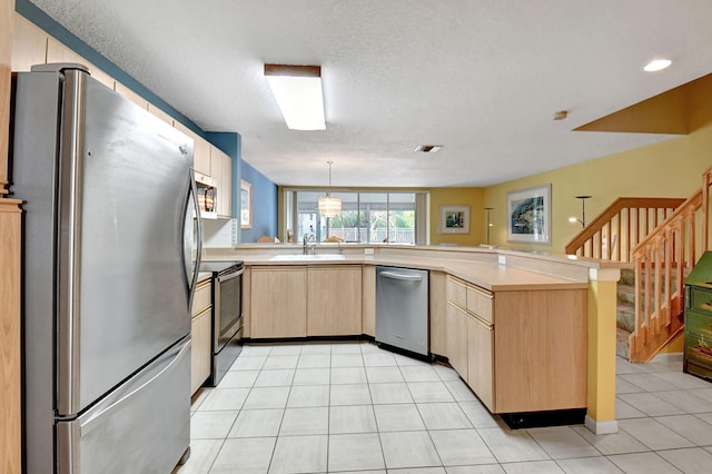 kitchen with light tile flooring, pendant lighting, kitchen peninsula, and stainless steel appliances