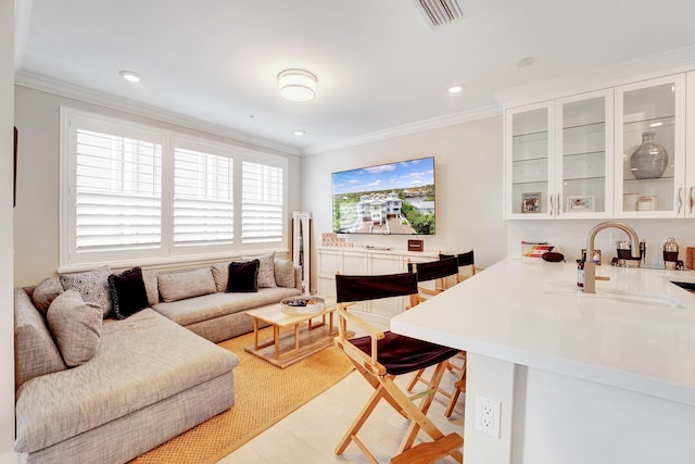 living room with light hardwood / wood-style flooring, ornamental molding, and sink