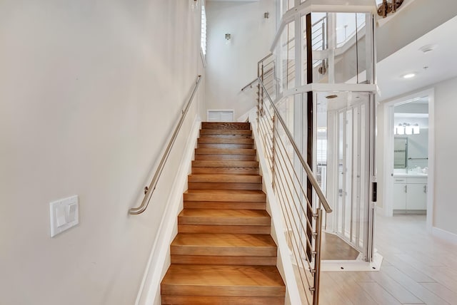 staircase featuring hardwood / wood-style floors and a towering ceiling