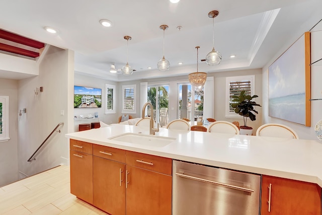 kitchen featuring sink, stainless steel dishwasher, a tray ceiling, decorative light fixtures, and a kitchen bar