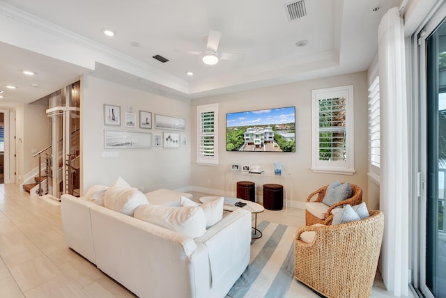 tiled living room featuring a raised ceiling, ceiling fan, and ornamental molding