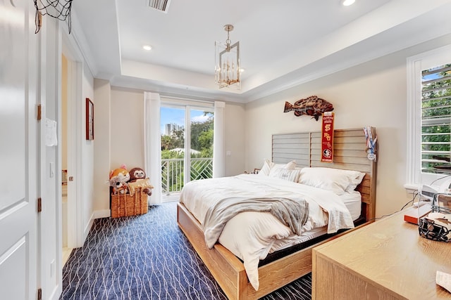 bedroom with a raised ceiling, multiple windows, a notable chandelier, and access to outside