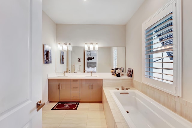 bathroom featuring tile patterned floors, vanity, and tiled bath