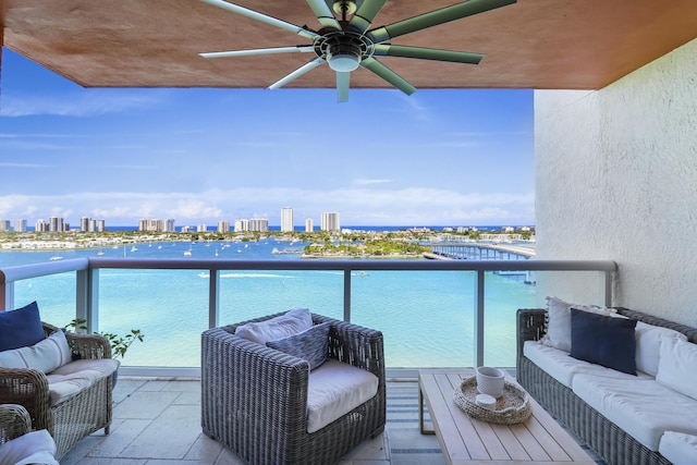 balcony featuring ceiling fan, a water view, and an outdoor living space