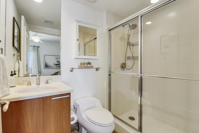 bathroom with ceiling fan, toilet, an enclosed shower, and vanity