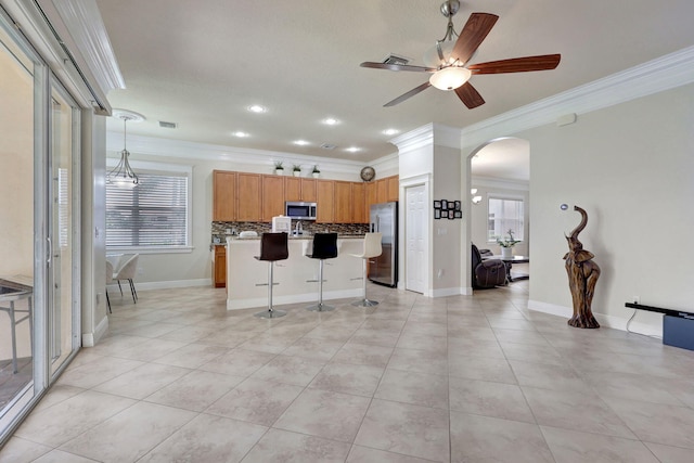 kitchen featuring a kitchen bar, ornamental molding, stainless steel appliances, decorative light fixtures, and a center island