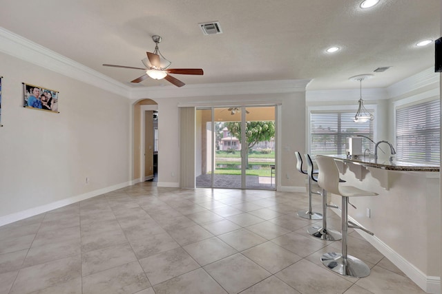 interior space with a textured ceiling, crown molding, ceiling fan, and light tile patterned floors