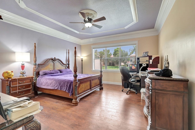 bedroom with ornamental molding, a textured ceiling, a raised ceiling, ceiling fan, and hardwood / wood-style floors