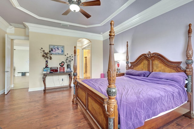 bedroom with dark hardwood / wood-style flooring, a tray ceiling, ceiling fan, and ornamental molding