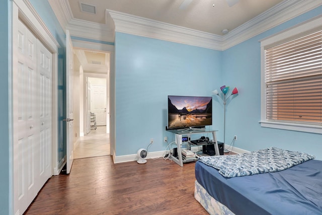 bedroom featuring dark wood-type flooring, a closet, ceiling fan, and ornamental molding