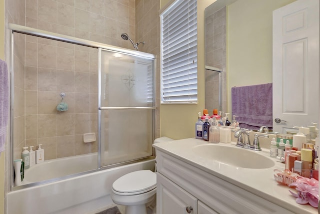 full bathroom featuring combined bath / shower with glass door, vanity, and toilet