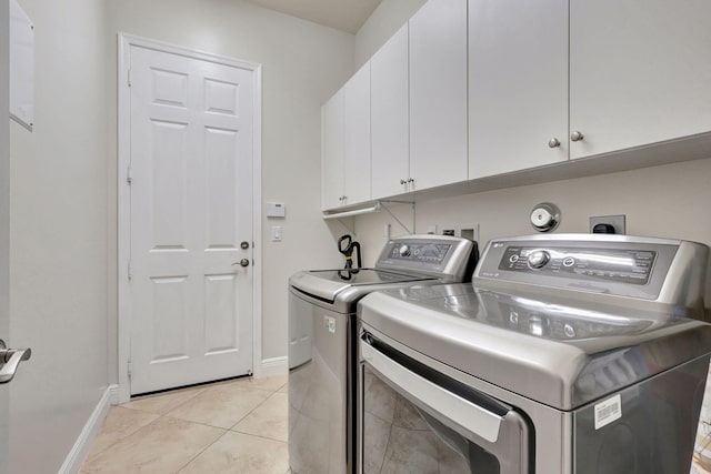 laundry area featuring washer and dryer, light tile patterned floors, and cabinets