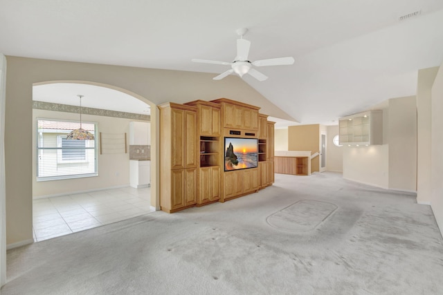 unfurnished living room with vaulted ceiling, ceiling fan, and light tile flooring