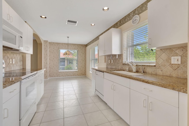 kitchen with tasteful backsplash, white appliances, pendant lighting, light tile floors, and white cabinetry