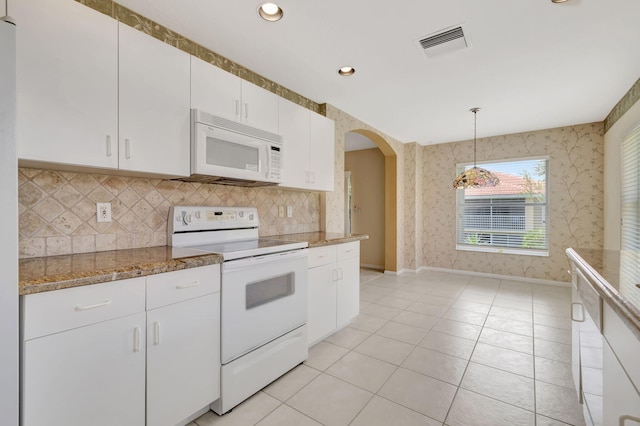 kitchen featuring decorative light fixtures, stone countertops, white cabinetry, white appliances, and light tile floors