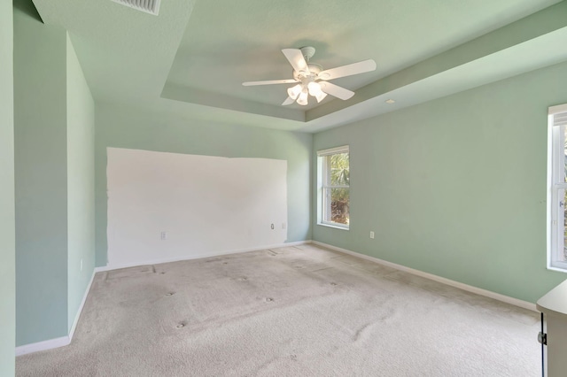 carpeted spare room featuring ceiling fan and a tray ceiling