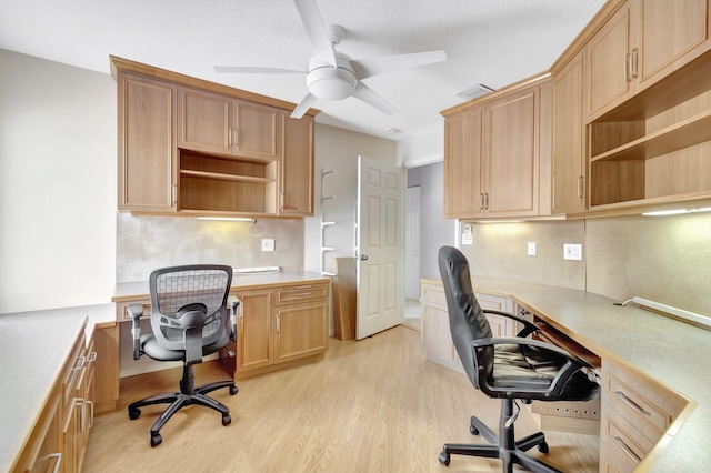 office area with ceiling fan, light hardwood / wood-style floors, and built in desk