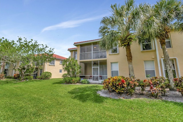 back of property featuring a sunroom and a lawn