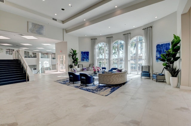 living room featuring a towering ceiling, light tile flooring, and a raised ceiling