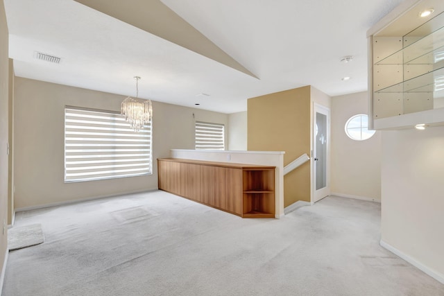 carpeted empty room with vaulted ceiling and a chandelier