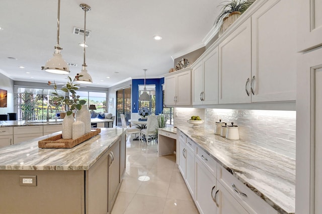 kitchen with white cabinets, light stone countertops, decorative light fixtures, and a kitchen island