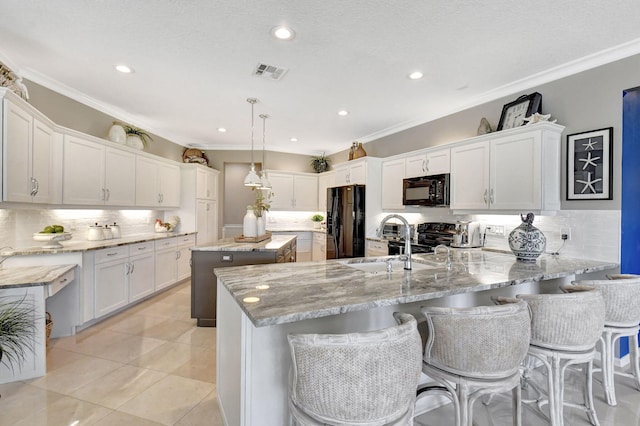 kitchen featuring white cabinets, black appliances, decorative light fixtures, and a center island