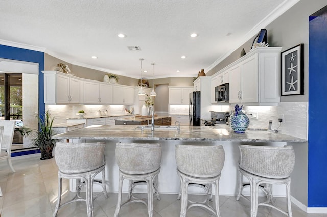 kitchen featuring black appliances, white cabinetry, hanging light fixtures, and ornamental molding