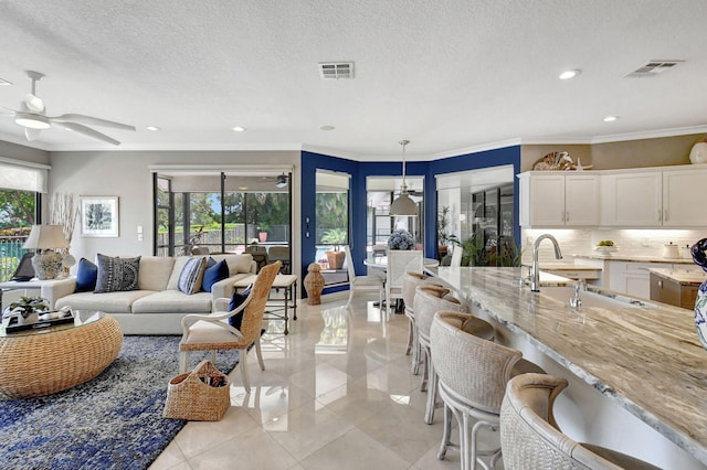 tiled living room featuring a wealth of natural light, a textured ceiling, and crown molding