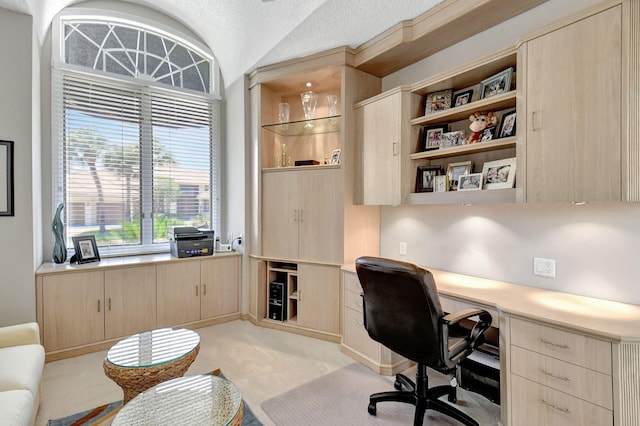 home office featuring built in desk, light colored carpet, a textured ceiling, and vaulted ceiling