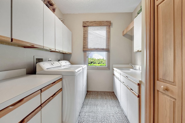 laundry room with cabinets, washing machine and dryer, a textured ceiling, and sink