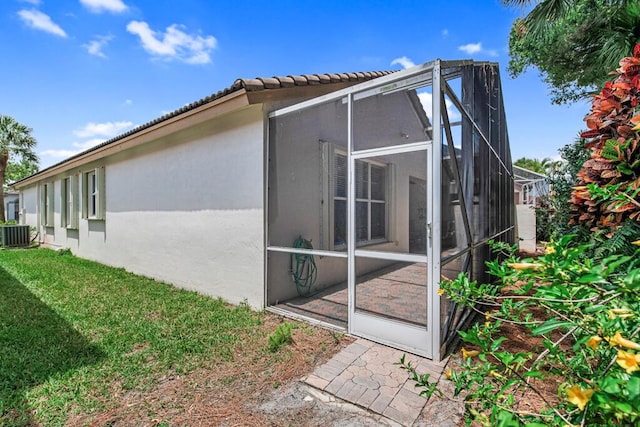 view of side of property featuring central air condition unit and a lawn