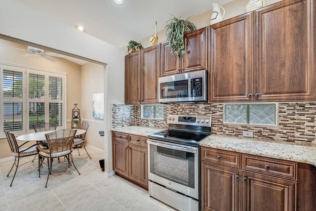 kitchen featuring ceiling fan, light stone countertops, stainless steel appliances, and tasteful backsplash