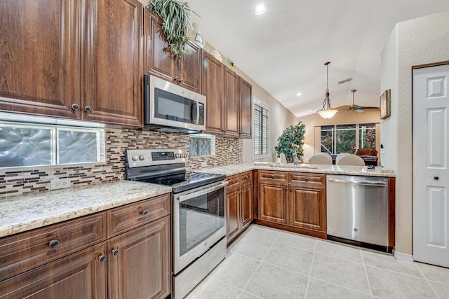 kitchen featuring stainless steel appliances, backsplash, decorative light fixtures, light stone countertops, and vaulted ceiling