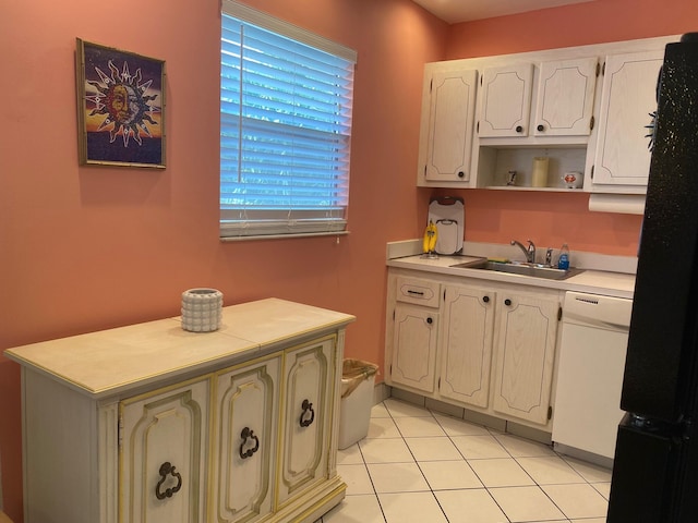 kitchen featuring black refrigerator, white cabinetry, dishwasher, sink, and light tile patterned floors