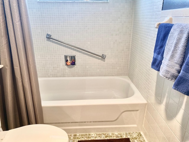 bathroom with tile walls, tile floors, shower / bath combination with curtain, and toilet