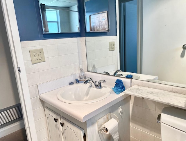 bathroom featuring vanity with extensive cabinet space, tile walls, and toilet