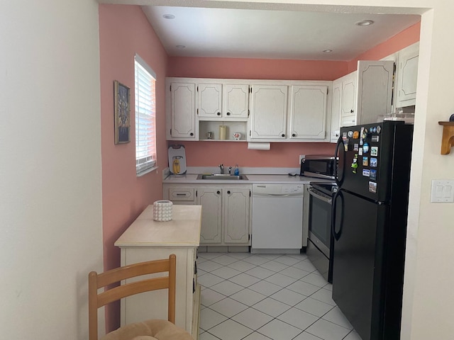 kitchen featuring dishwasher, black fridge, range with electric cooktop, white cabinetry, and sink