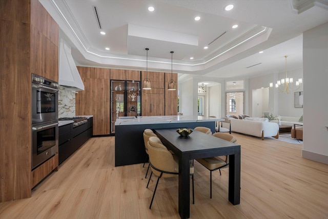 dining room with light hardwood / wood-style floors, a raised ceiling, and sink