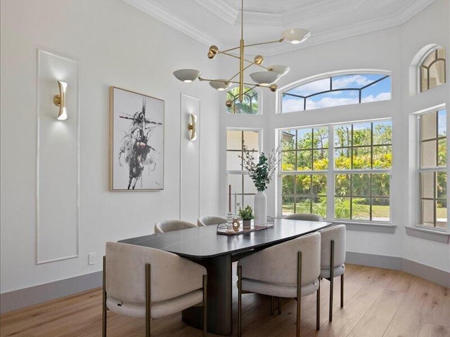 dining space with light wood-type flooring, ornamental molding, and a chandelier