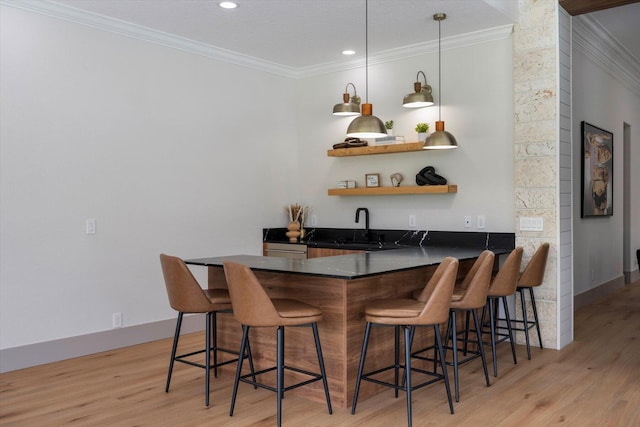 bar featuring ornamental molding, sink, pendant lighting, and light wood-type flooring