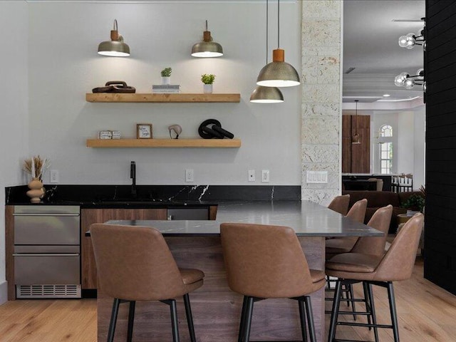 bar with wood-type flooring, sink, and hanging light fixtures