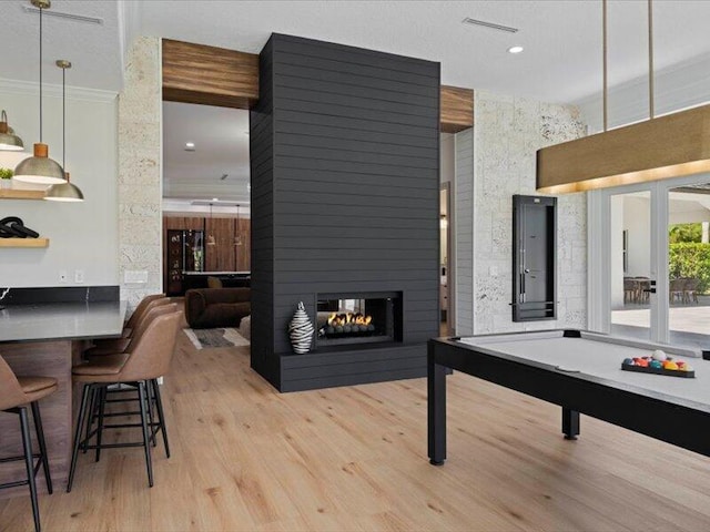 recreation room with french doors, a multi sided fireplace, crown molding, light wood-type flooring, and pool table