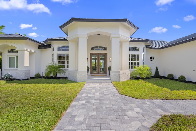 doorway to property featuring a lawn and french doors