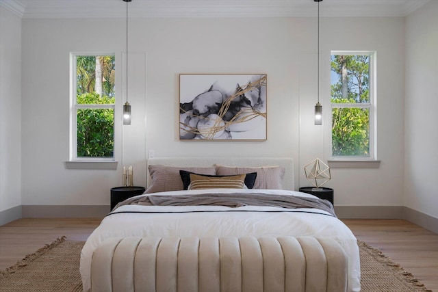 bedroom with multiple windows, ornamental molding, and light wood-type flooring