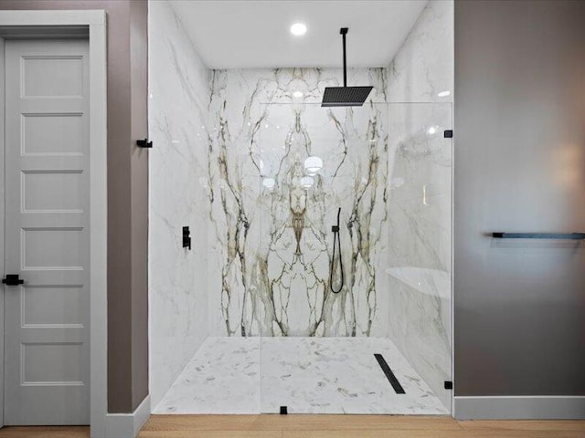 bathroom with tiled shower and hardwood / wood-style floors