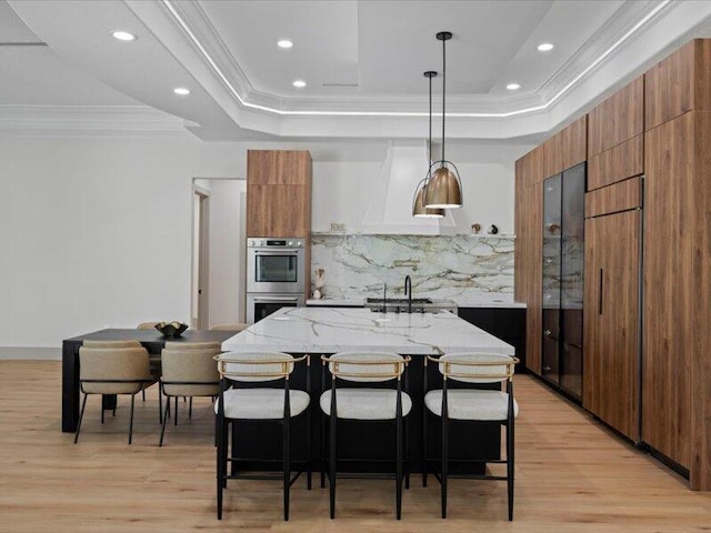 kitchen with tasteful backsplash, a kitchen bar, pendant lighting, and light hardwood / wood-style floors