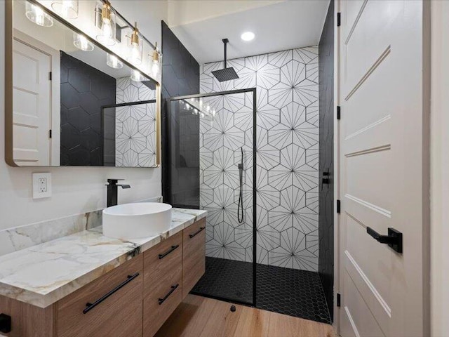 bathroom with a tile shower, vanity, and hardwood / wood-style flooring