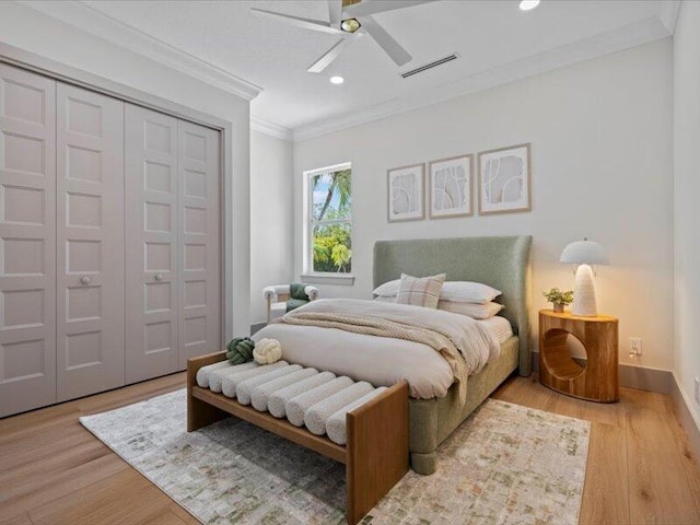 bedroom featuring light wood-type flooring, a closet, ceiling fan, and crown molding