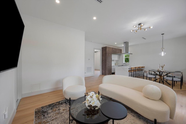 living room with light hardwood / wood-style flooring, a chandelier, and sink