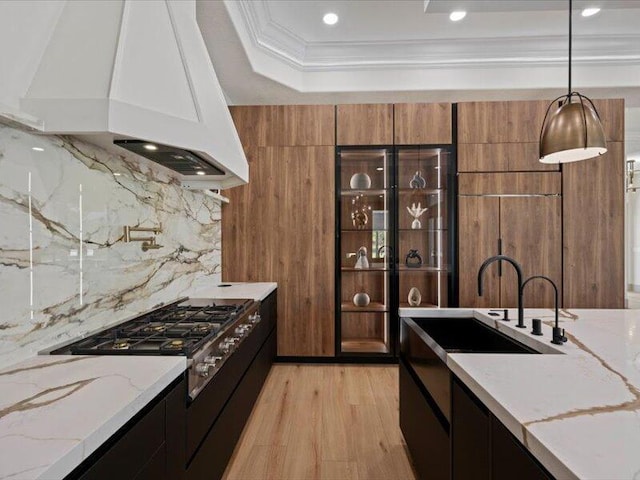 kitchen featuring decorative backsplash, custom range hood, light hardwood / wood-style floors, and light stone counters